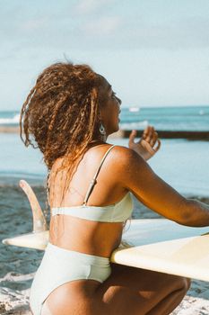 A woman enjoying a sunny day at the beach with her surfboard, ready to catch some waves.