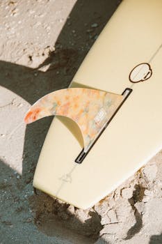 Surfboard fin resting on sand, capturing the essence of summer beach vibes.