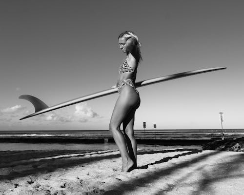 Grayscale Photo of a Sexy Woman in Leopard Print Bikini Holding a Surfboard