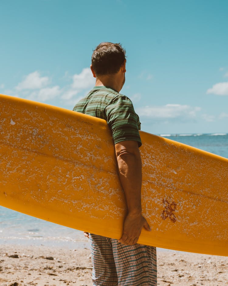 Man Holding Surfboard At Beach