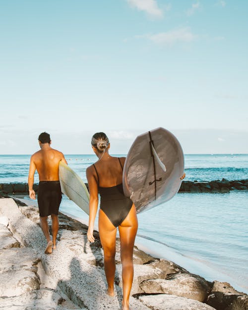 Free Man and Woman Carrying a Surfboards Stock Photo