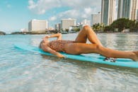 穿着泳衣的女人在热带海滩的冲浪板上闲逛，城市天际线