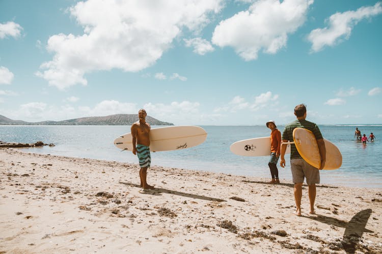 Men Carrying Surfboards While Standing At The Beach