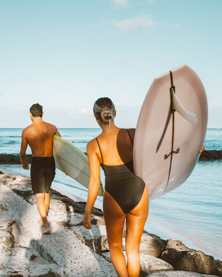 Man And Woman Carrying Surfboards While Walking