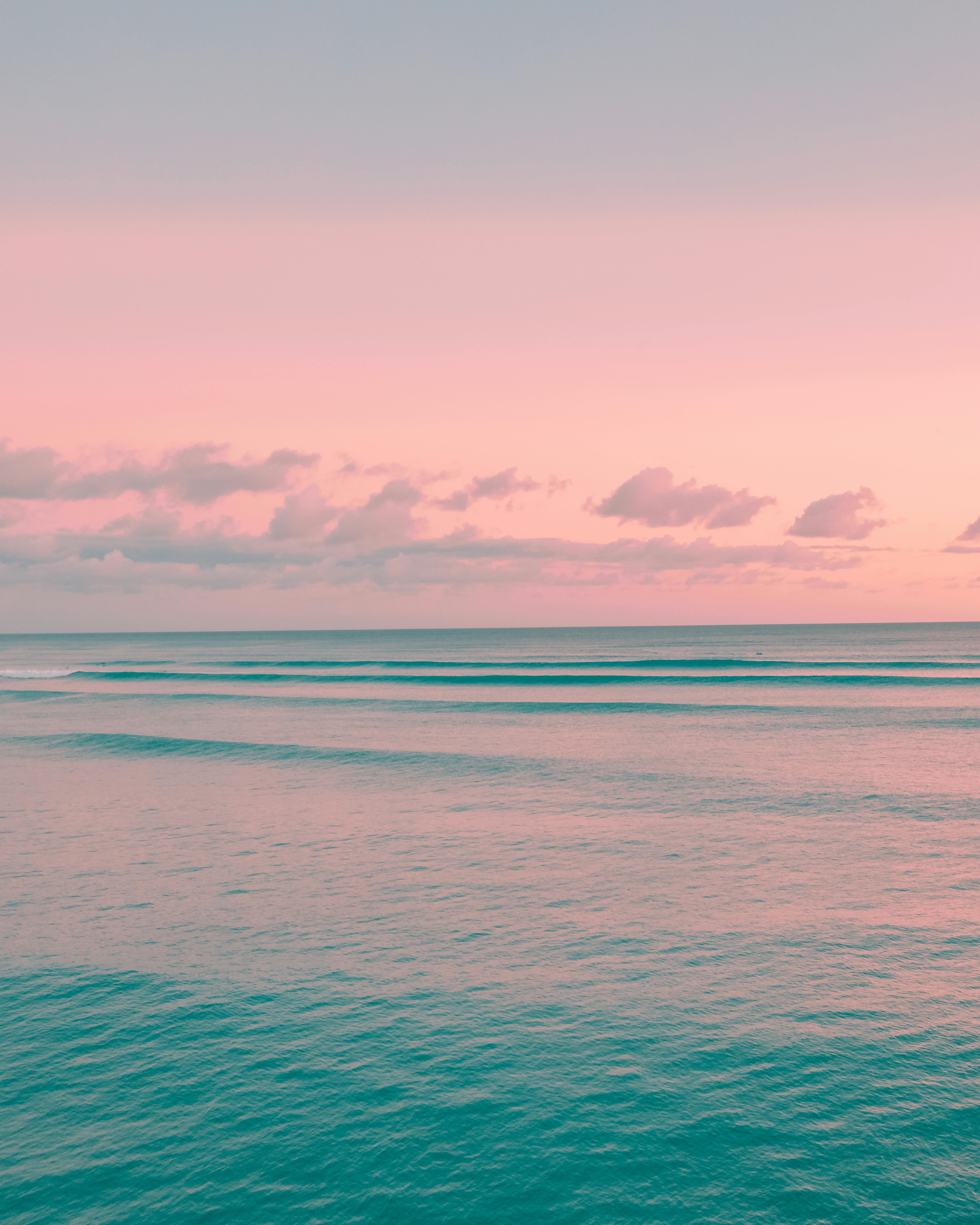 美丽的日出在海洋上，在天空和水上投下粉红色和蓝色的色调