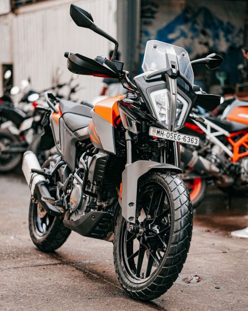 Free Orange and black motorcycle parked outdoors in an urban setting, side view. Stock Photo