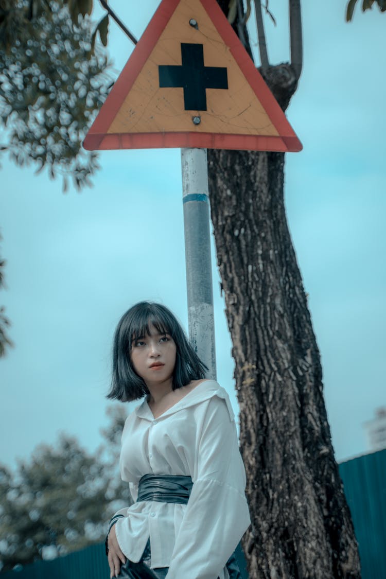 Brunette Girl Standing Under A Road Sign With Cross