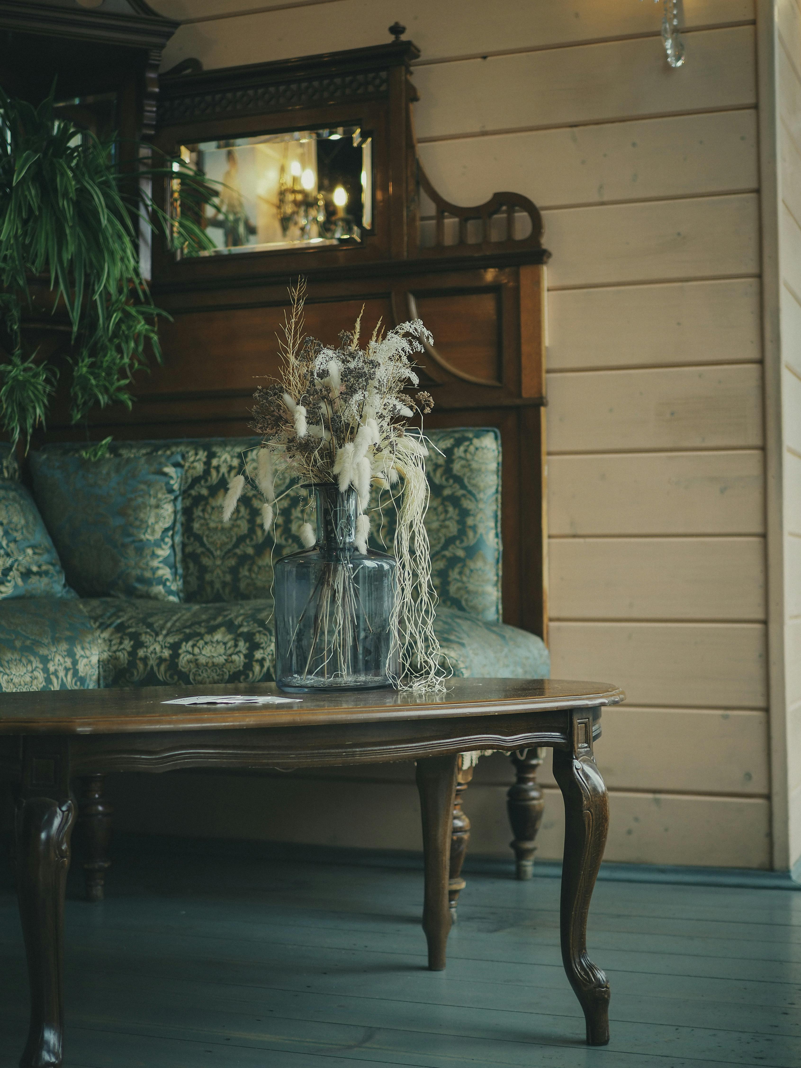 A cozy living room with vintage furniture, featuring a glass vase on a wooden table.