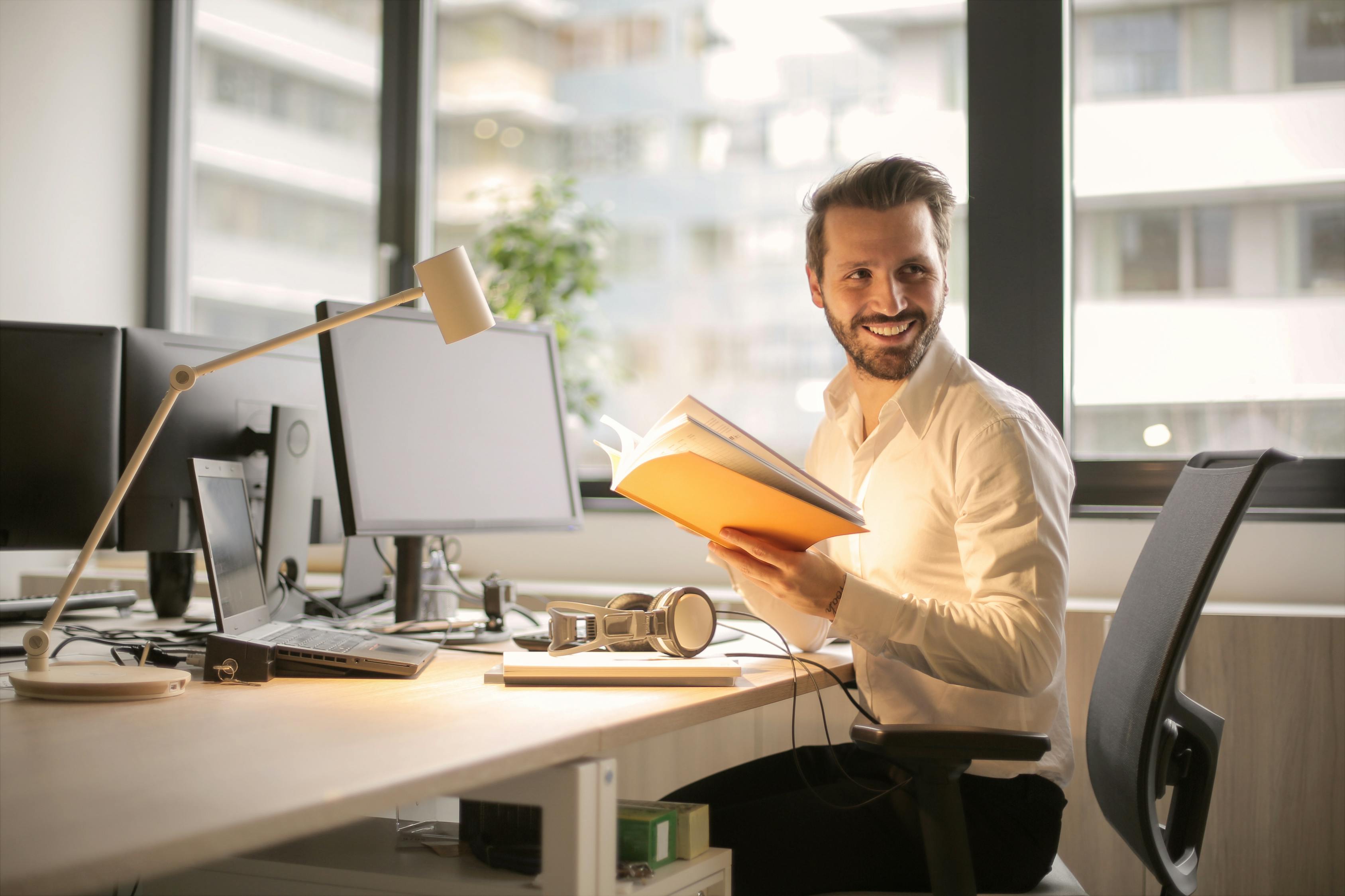 Photo of a businessman in office holding a book and smiling