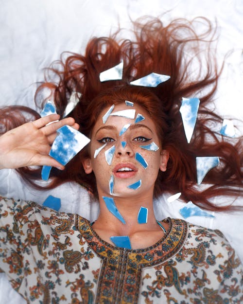 Woman Lying with Broken Pieces of a Photograph of Sky around Her 