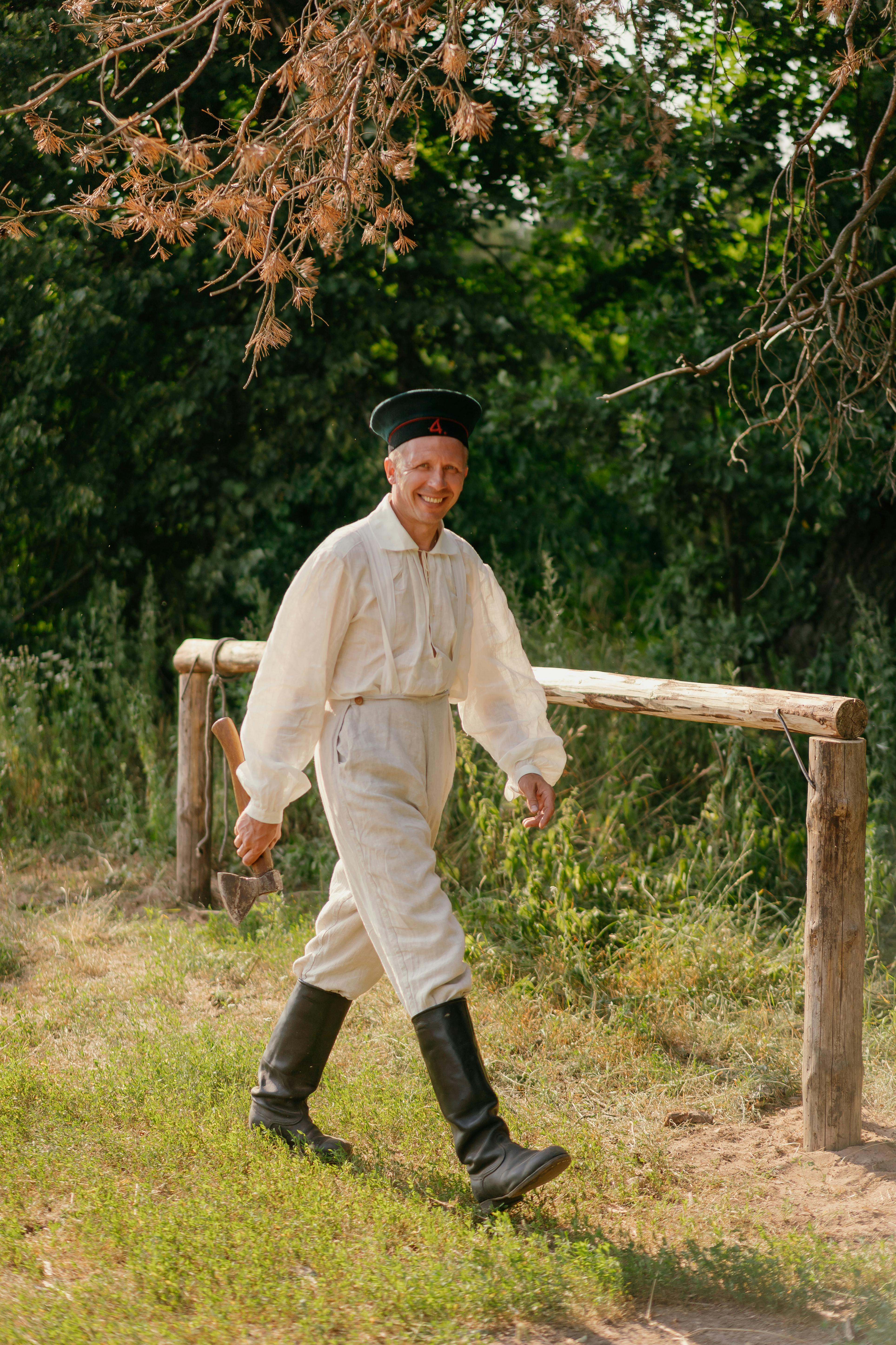 A man wearing a traditional Russian military uniform from the past walks outdoors, smiling.