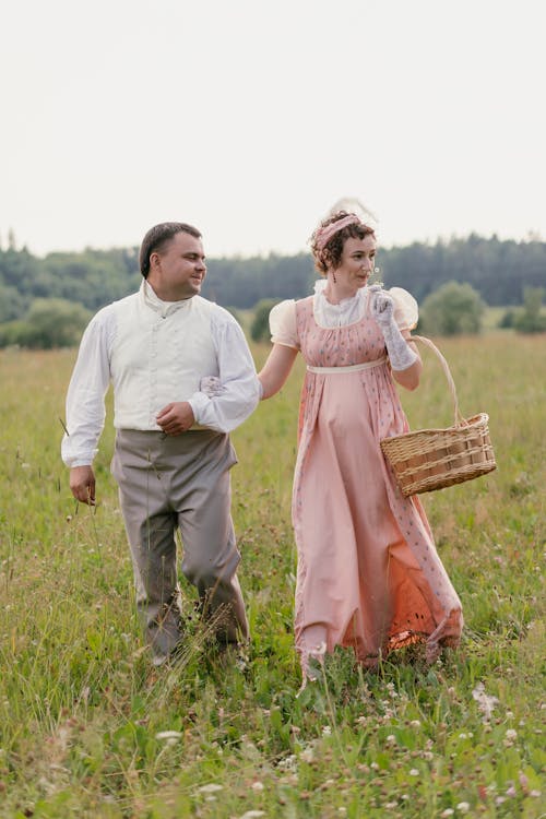 A Couple in Historical Costumes Walking on a Meadow 