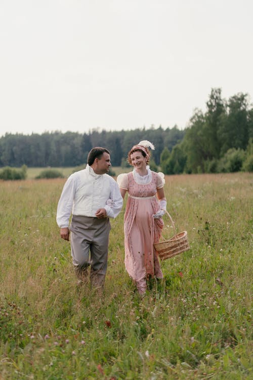 A Couple in Historical Costumes Walking on a Meadow 