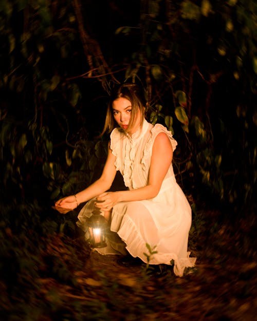 Woman in White Dress Holding a Kerosene Lamp