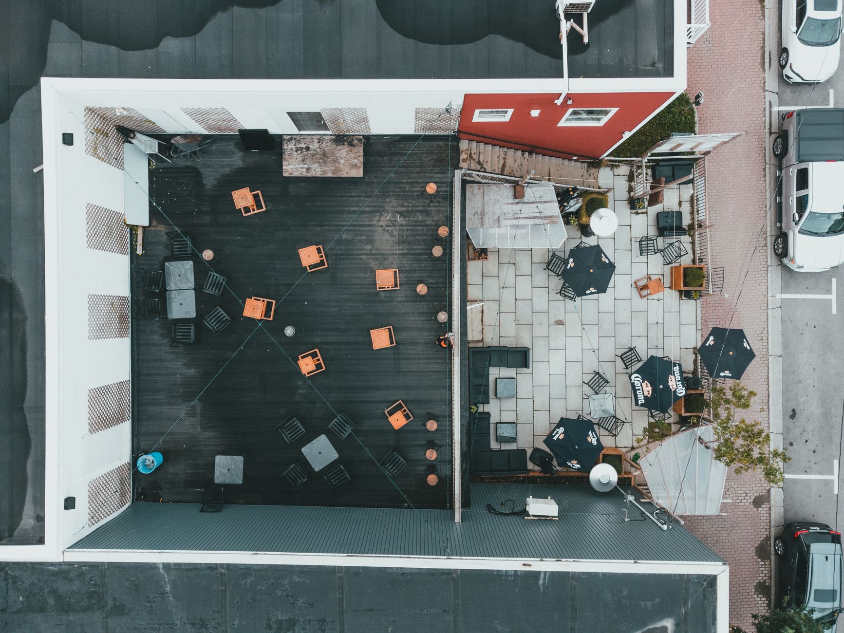 Aerial shot of a stylish outdoor patio with tables and chairs arranged in a commercial building setting.