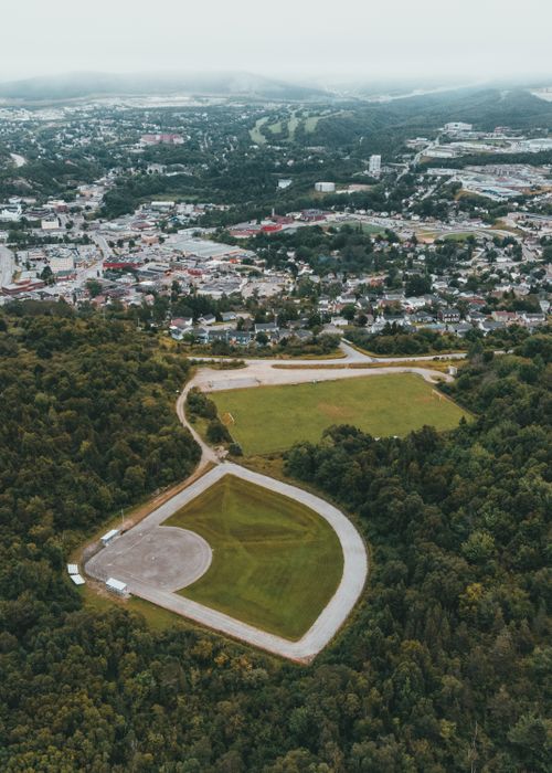 Free An aerial photo capturing a city's blend of urban areas and surrounding lush greenery, featuring a sports field. Stock Photo