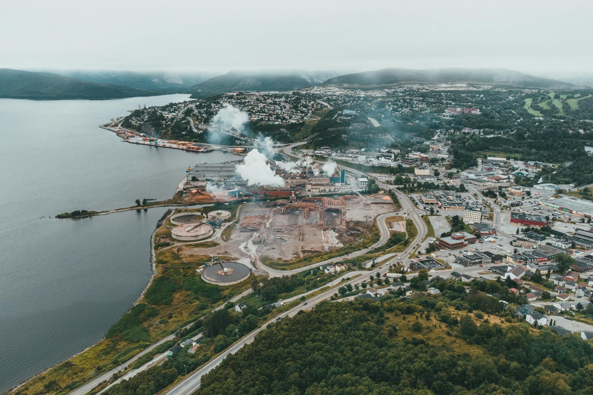 Aerial view capturing an industrial coastal town with factories and lush greenery.