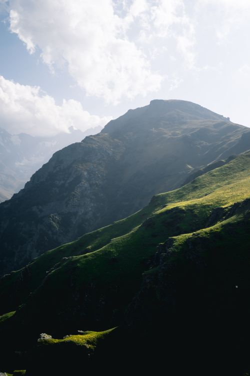 Free Stunning view of a sunlit mountain peak with lush greenery, captured in a vertical shot. Stock Photo