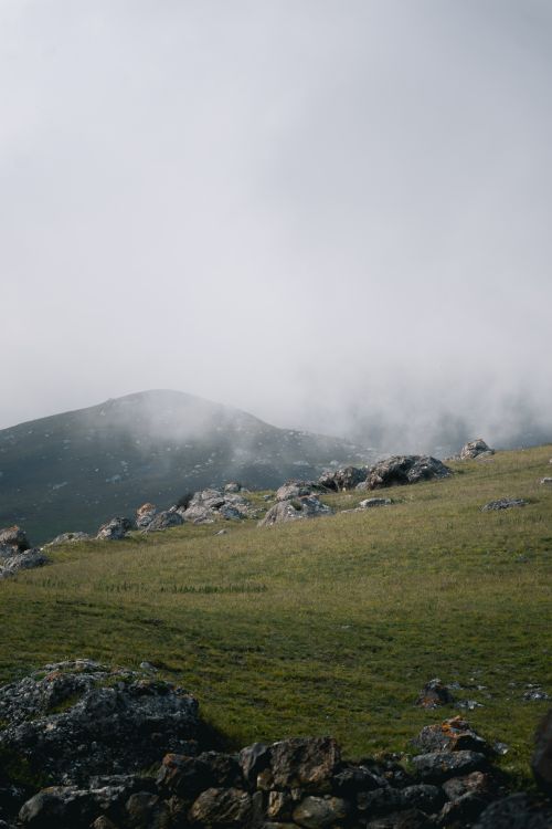 Free Tranquil fog-covered mountain with rocky meadow, offering a peaceful natural scene. Stock Photo
