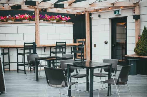 Free Modern outdoor cafe with stylish seating and a variety of colorful flowers. Stock Photo
