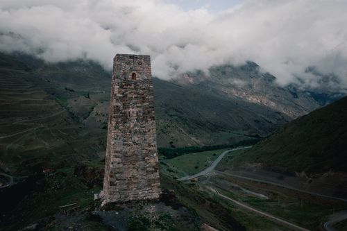 Free Explore the historic stone tower in a mountainous landscape shrouded in clouds. Stock Photo
