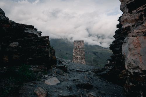 Free Mysterious mountain scene with ancient tower and fog surrounding ruins creating an eerie atmosphere. Stock Photo