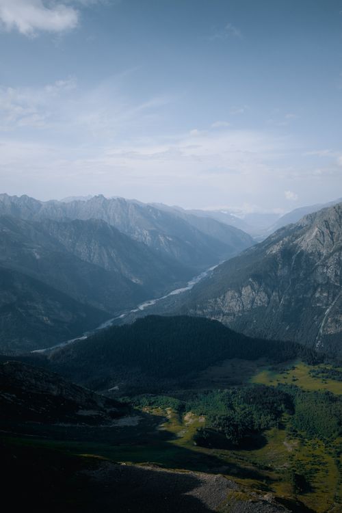 Free Scenic view of a vast mountain range with a lush green valley under a bright sky. Stock Photo