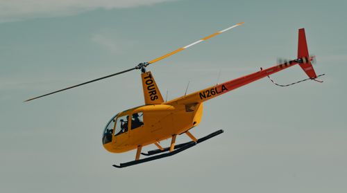 Free A bright yellow helicopter tours in flight, showcasing aerial travel against a clear sky. Stock Photo