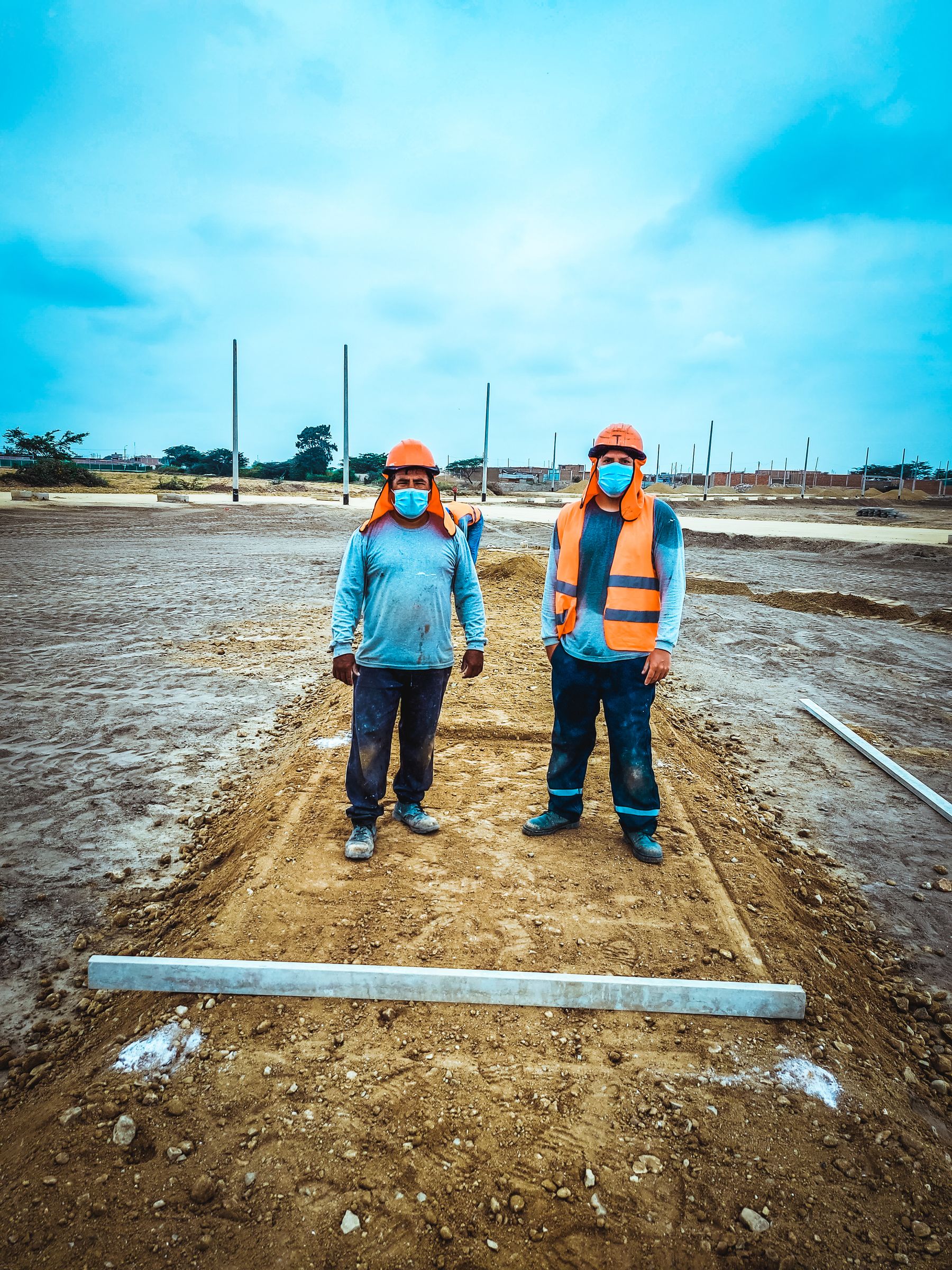 Construction workers wearing face masks and safety gear at an outdoor worksite