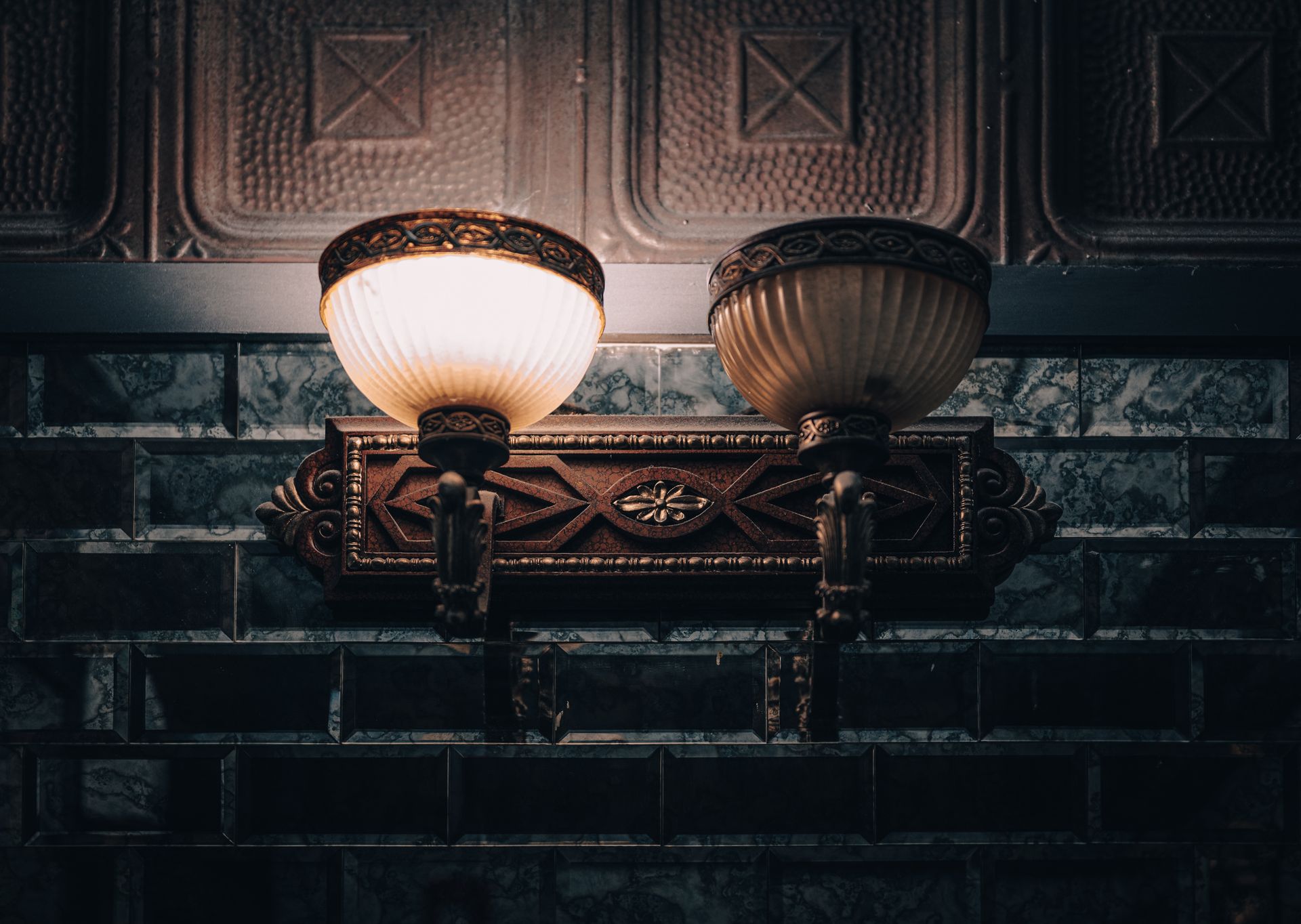 Close-up of elegant vintage wall lamps with ornate metalwork and glowing light.