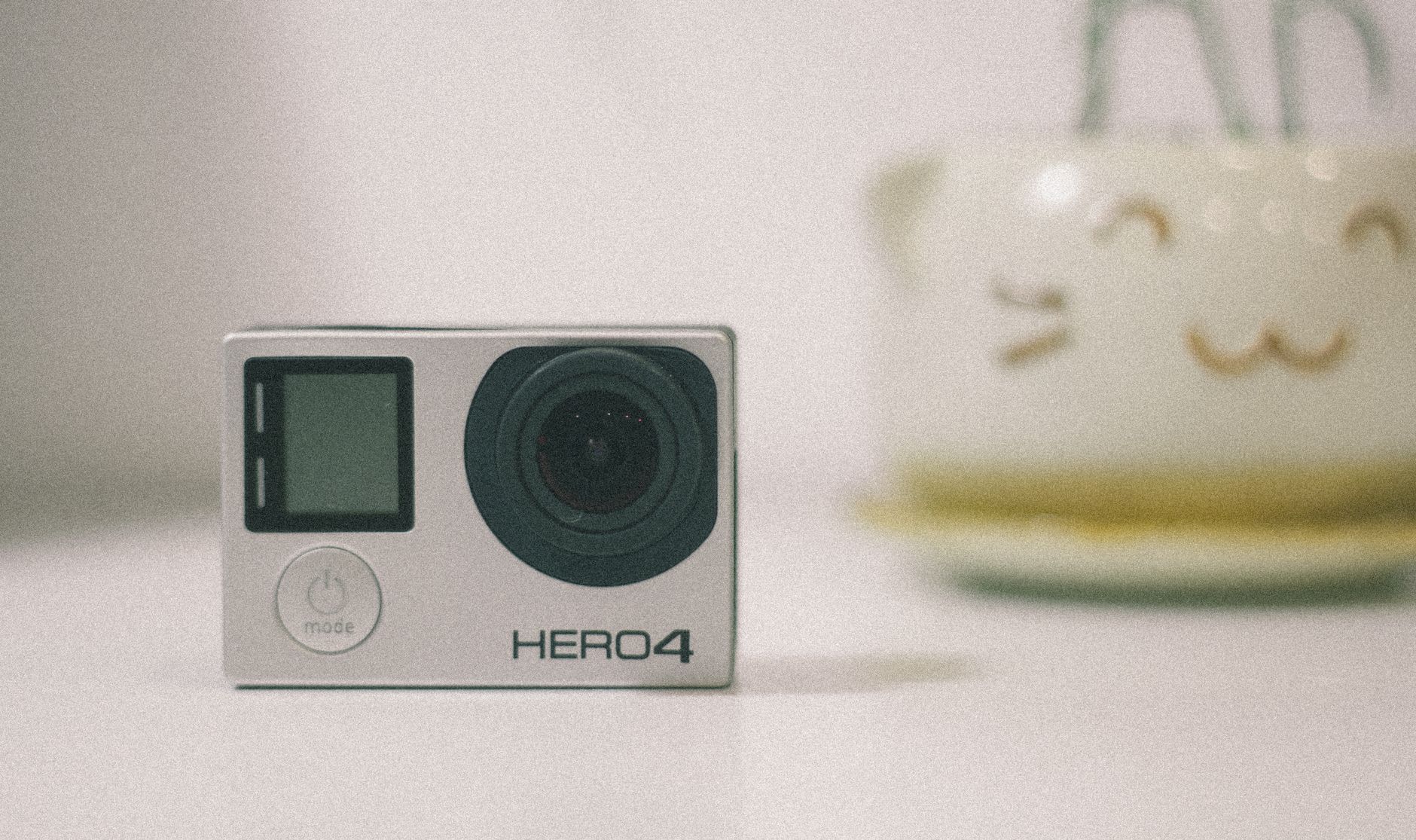 A GoPro Hero 4 action camera on a desk with soft lighting, suitable for technology themes.
