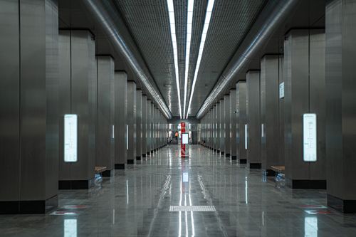 Free Modern underground subway station hallway featuring sleek metallic design and prominent directional signs. Stock Photo