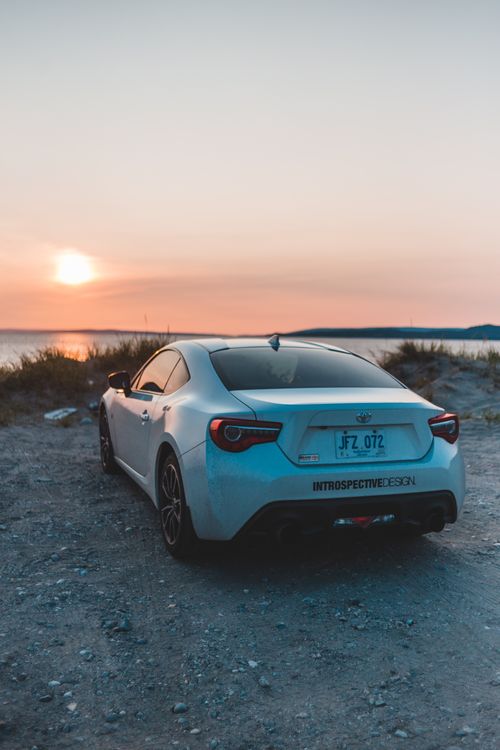 Free A parked sedan overlooks the sea at sunset creating a serene transportation scene. Stock Photo