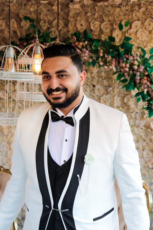 Man Wearing White Suit Standing Near Brow Wall