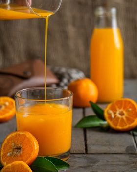 Vibrant orange juice being poured into a glass surrounded by fresh oranges, highlighting freshness and health.