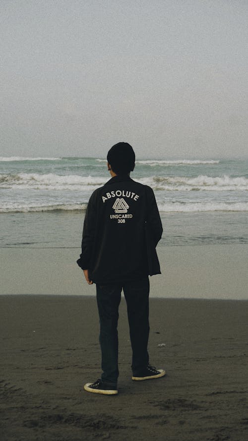 Man Wearing a Jacket Standing on the Beach