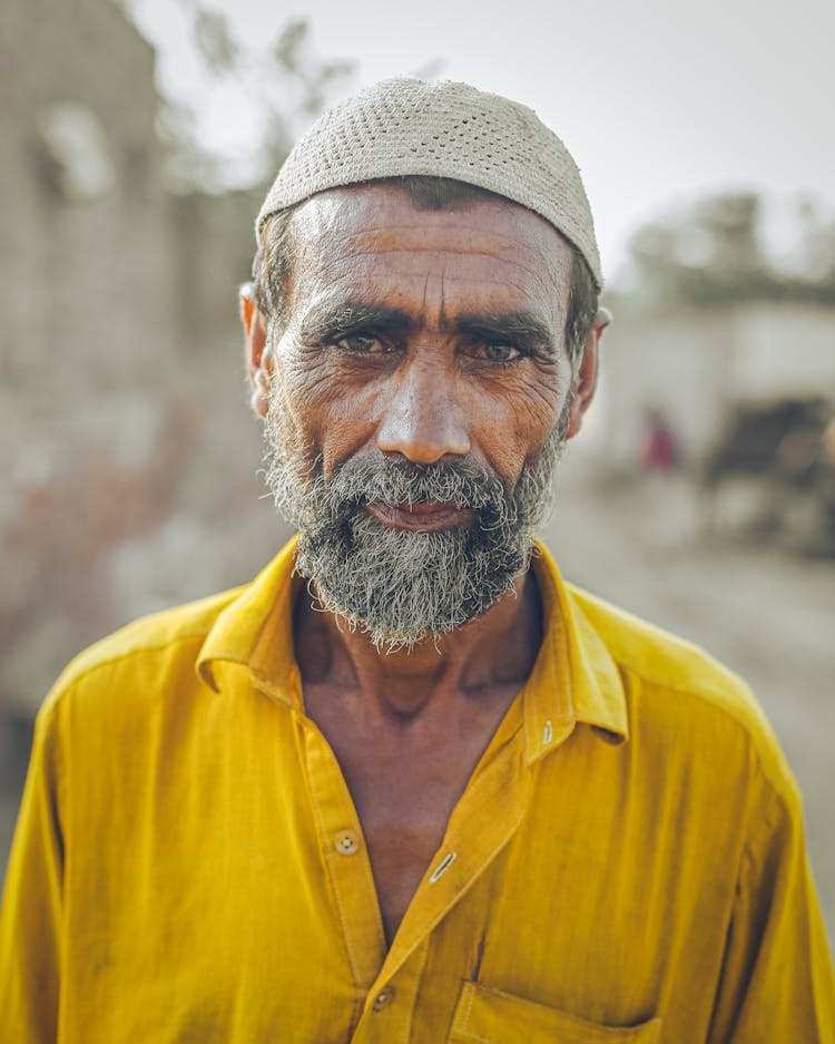 A Man In A Taqiyah And A Yellow Shirt