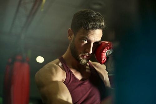 Free Bearded male boxer in gym focusing intensely during training session. Stock Photo