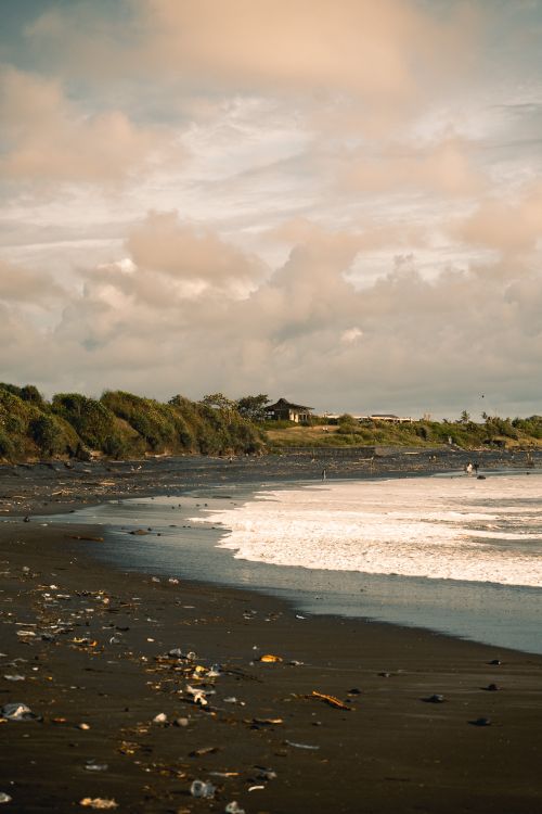 Free Dramatic clouds over a serene beach in Bali, Indonesia. Perfect for travel and nature themes. Stock Photo