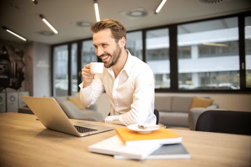 Free Depth of Field Photo of Man Sitting on Chair While Holding Cup in Front of Table Stock Photo