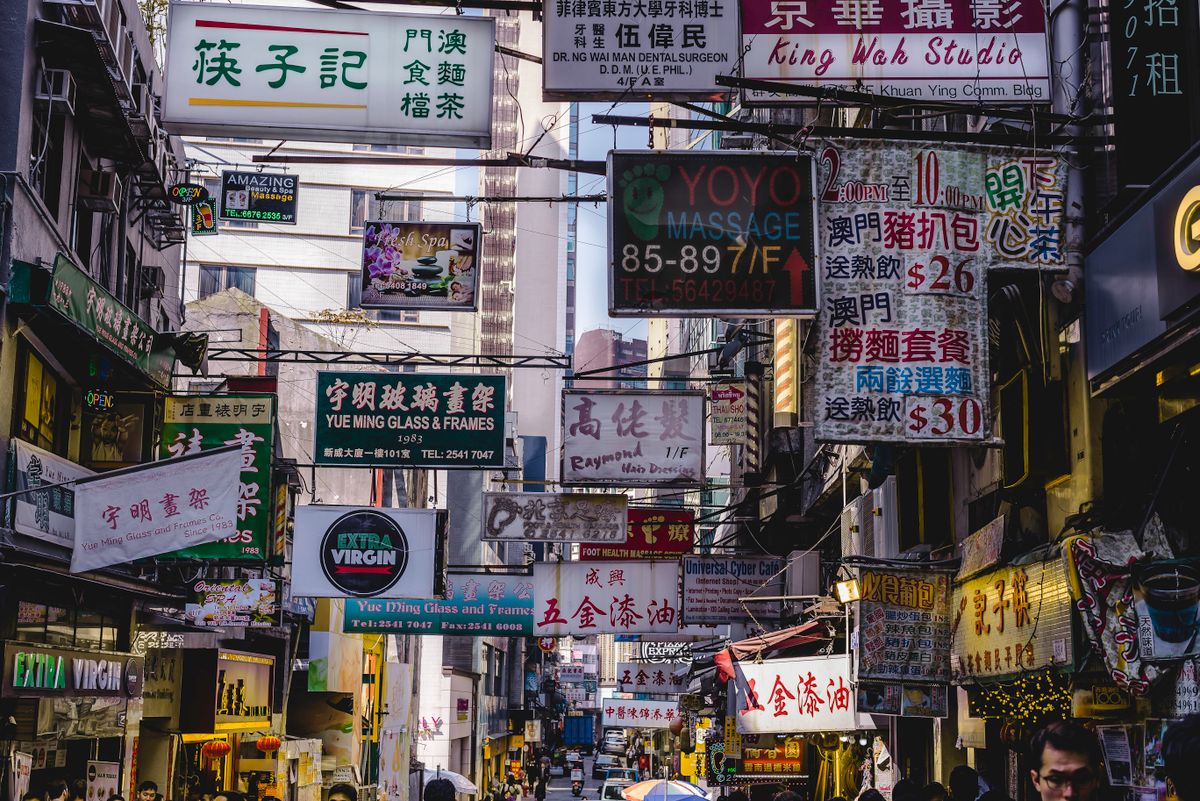 Colourful signage hanging above a busy street in Hong Kong