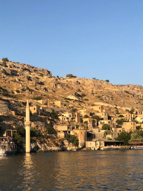 Free Charming historic stone town nestled by a tranquil riverside under a clear sky. Stock Photo