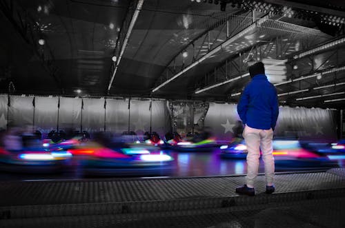 Man in Blue Jacket Staring at Bumper Cars
