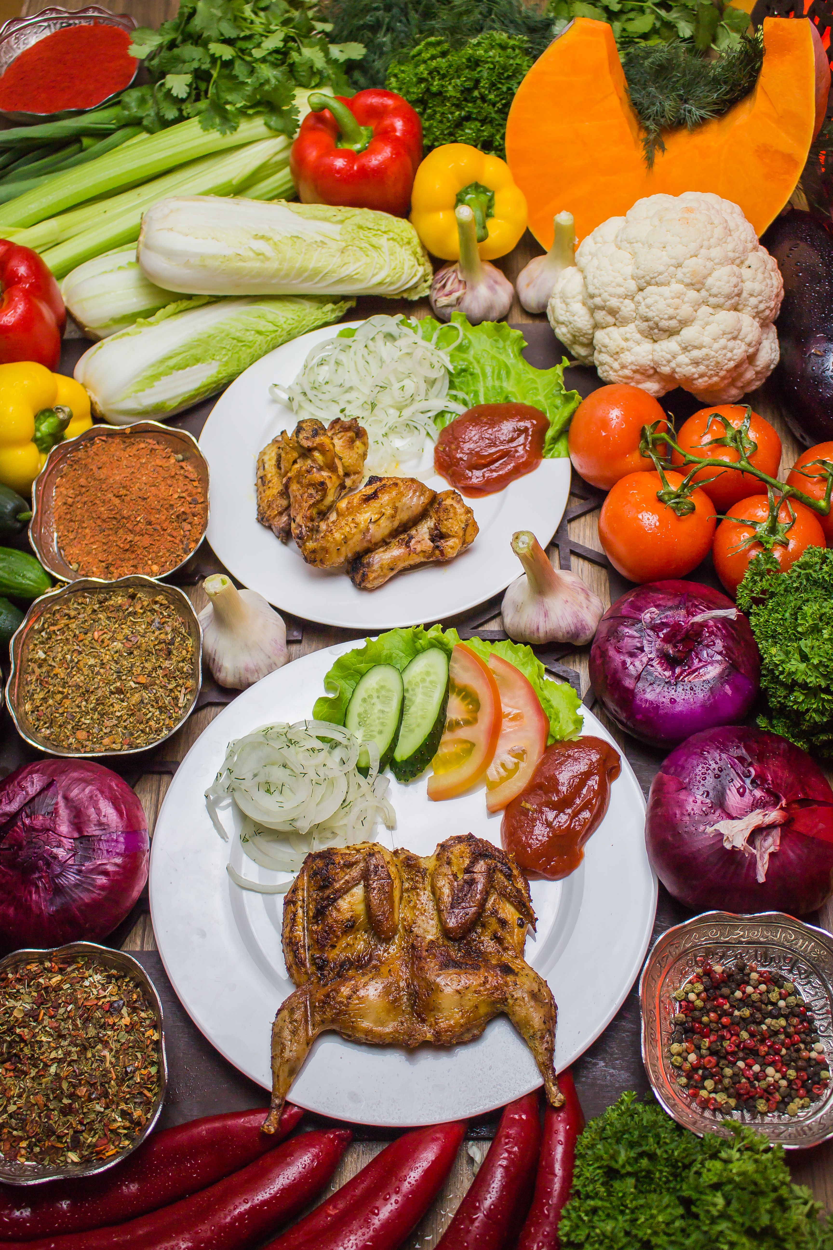 Vibrant display of roasted chicken surrounded by fresh vegetables and spices.