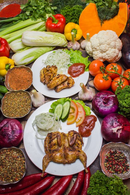 Free Vibrant display of roasted chicken surrounded by fresh vegetables and spices. Stock Photo