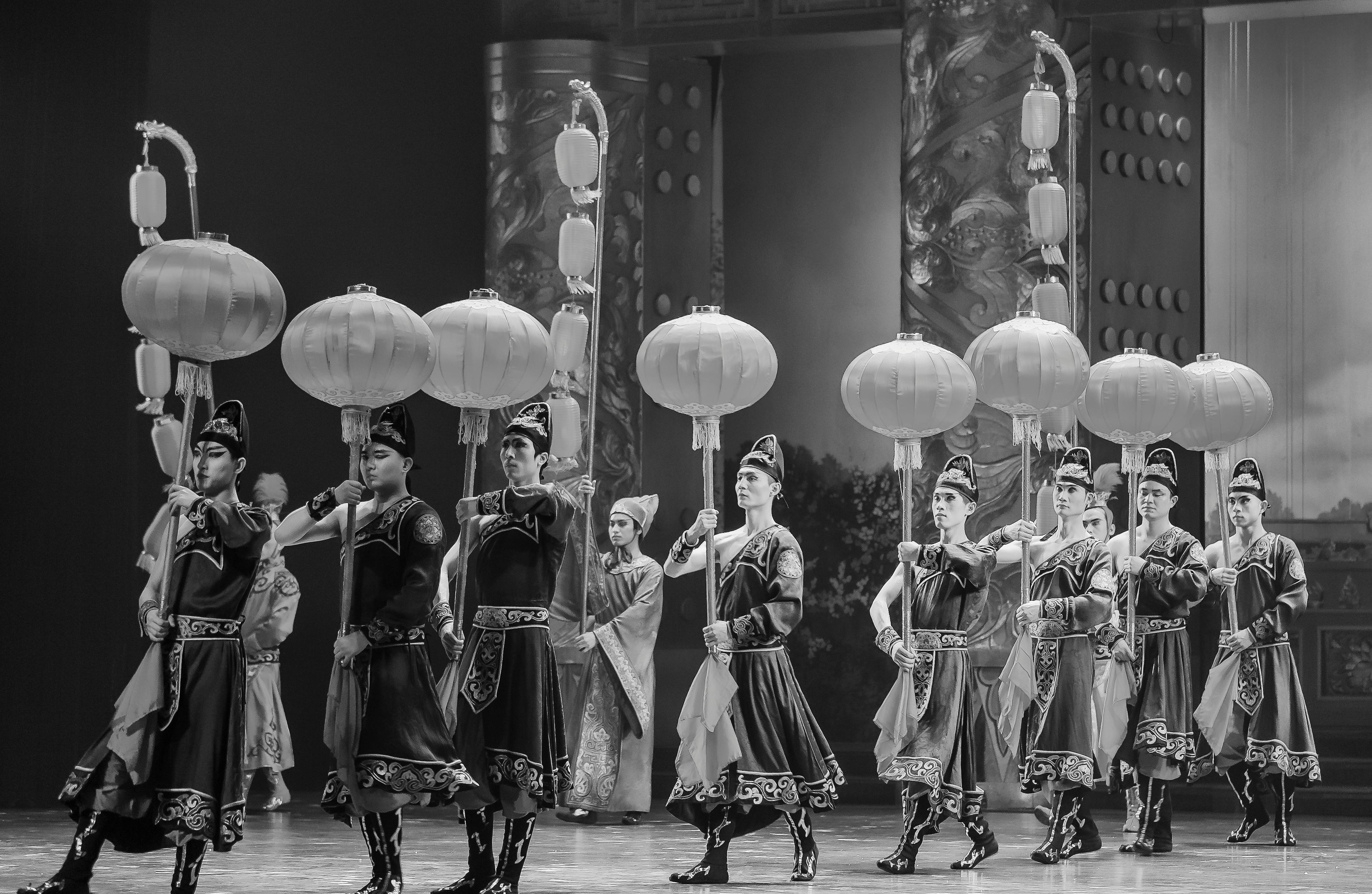 Free Black-and-white image of traditional dancers performing on stage with lanterns. Stock Photo