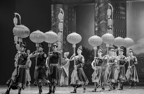 Grayscale Photo of a Group of People Performing on Stage