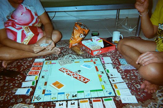 Group enjoying a lively game of Monopoly on a cozy carpet in Dubai.