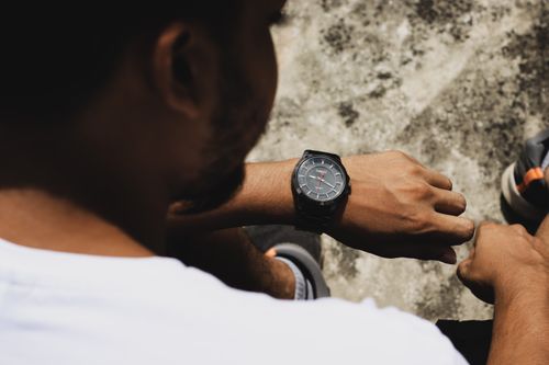 Free A man outdoors checking time on a stylish wristwatch, highlighting men's fashion. Stock Photo