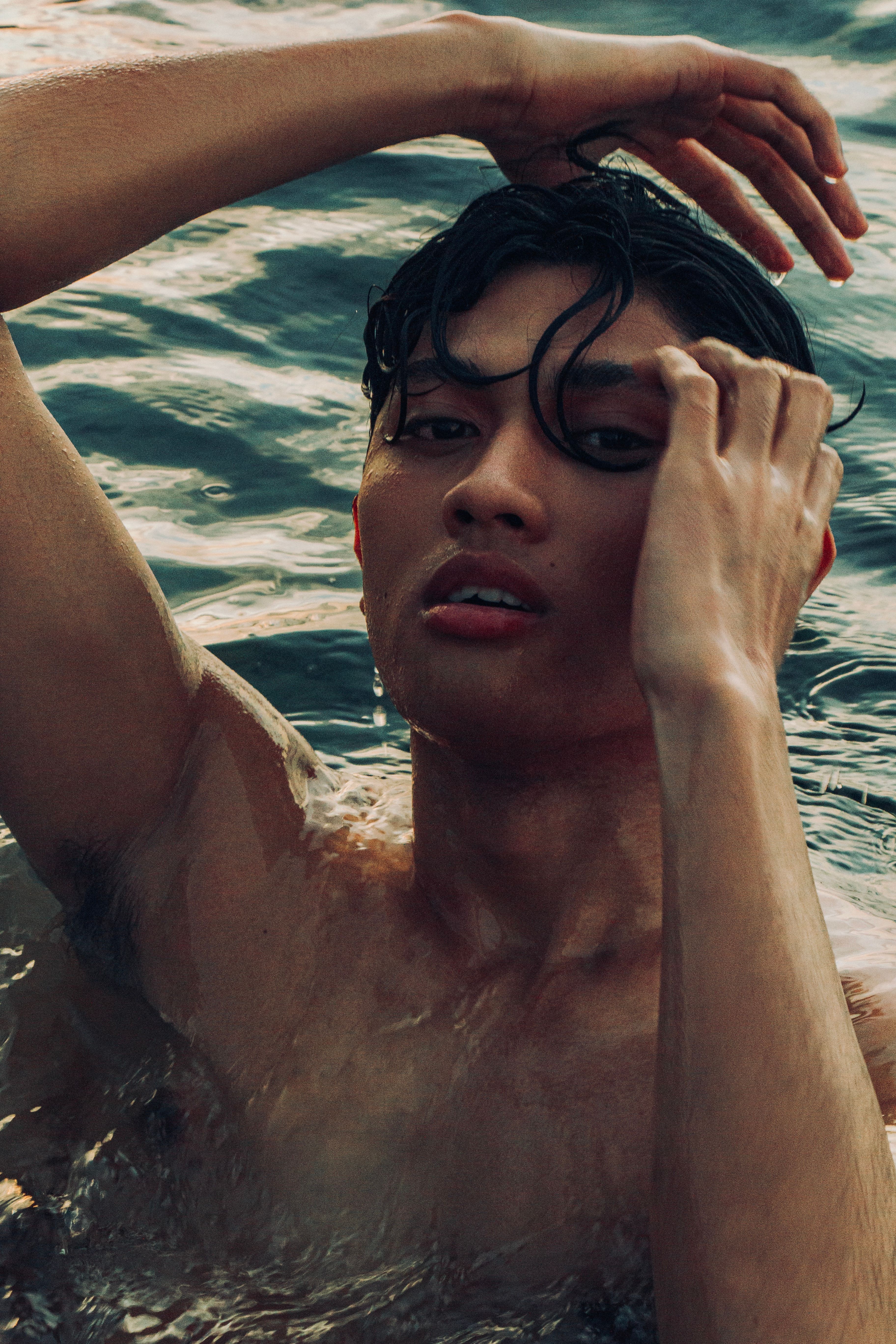 Close-up of a young man in water, emotional and artistic expression.